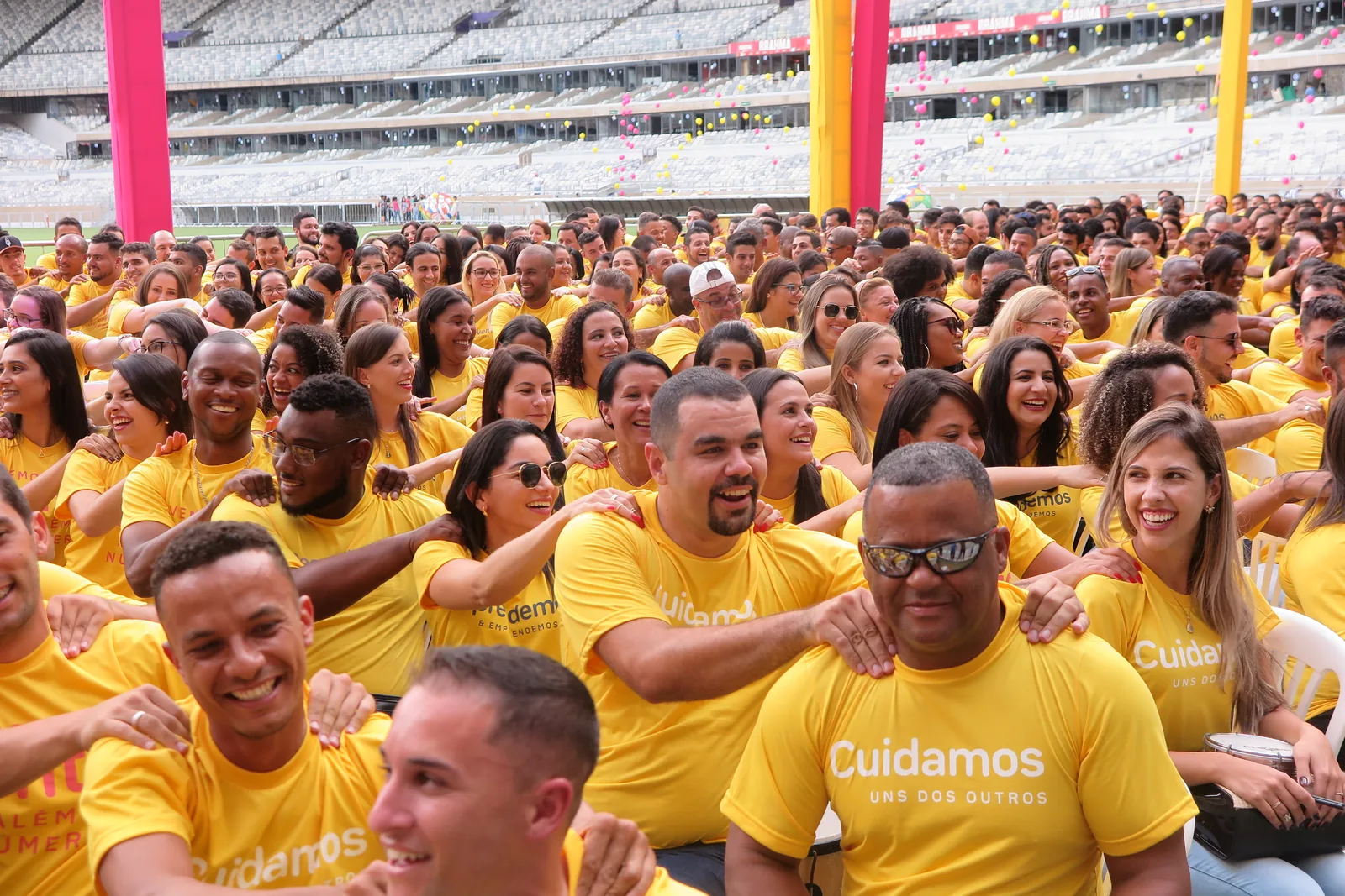 Centenas de colaboradores de camiseta amarela, rindo e conectados durante o Pratubatê no Mineirão